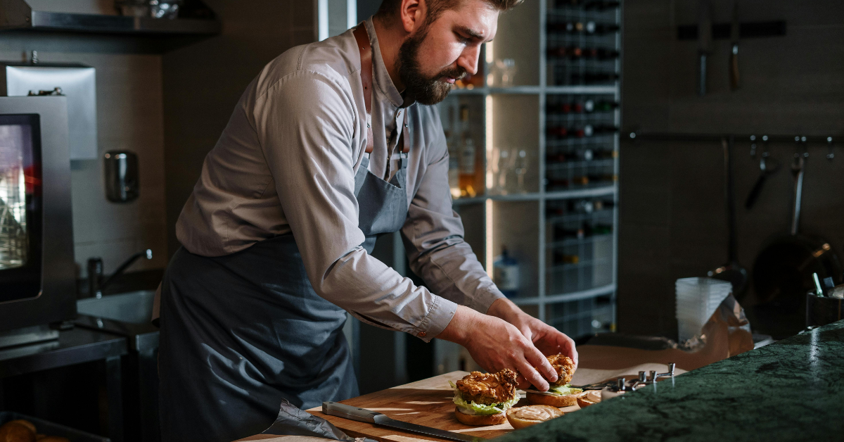 chef cuisinier avec tablier dressant une assiette